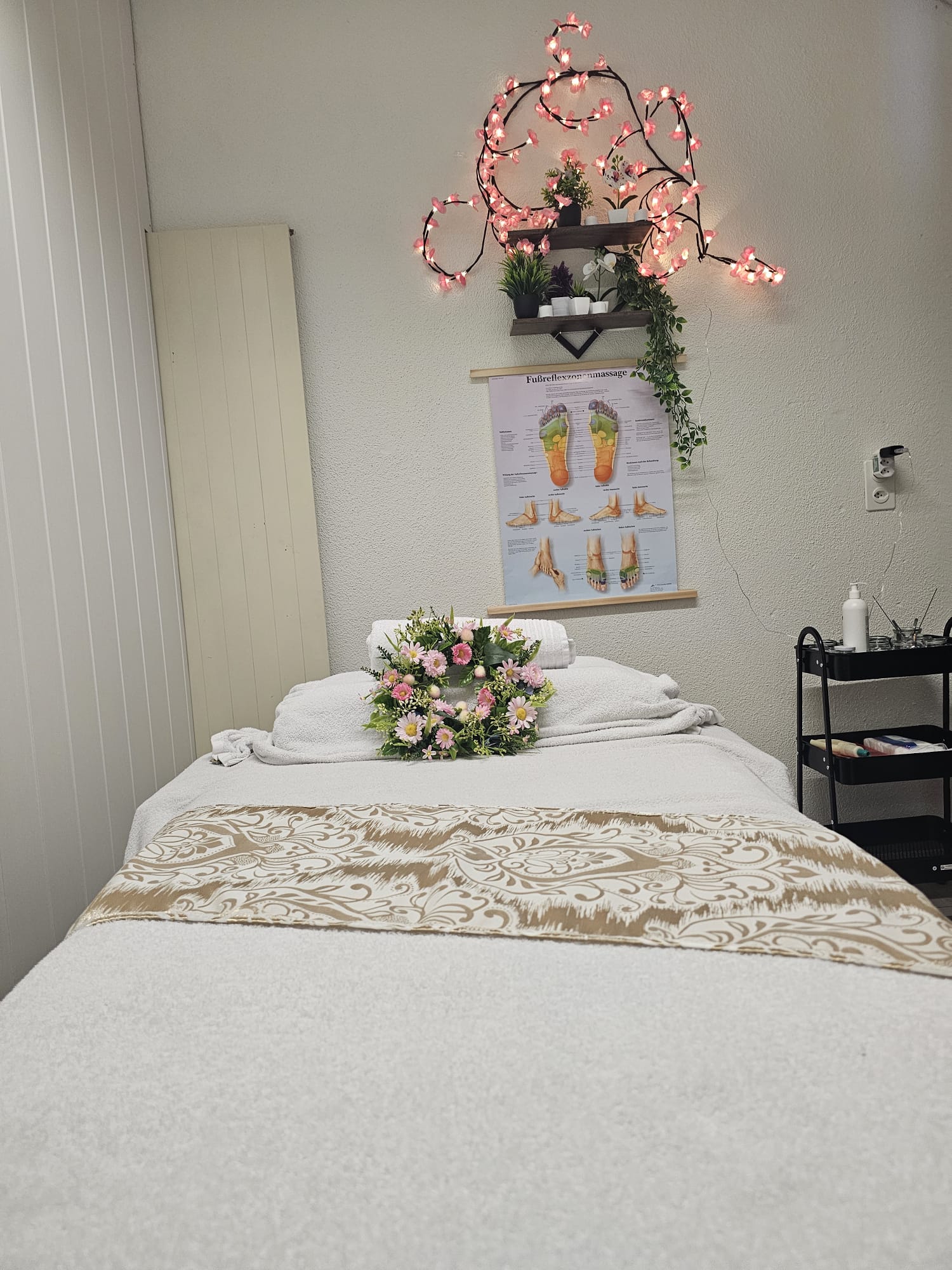 Gemütlicher Massageraum mit Blumenkranz und goldenem Läufer